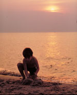 Photo of a boy playing with sand on a beach